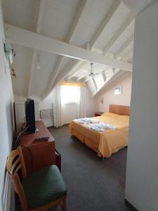 1 dormitorio con 1 cama y escritorio con TV en Belmar en Villa Gesell
