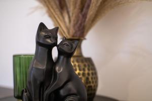 uma estátua de um gato preto sentado ao lado de um vaso em Lichterfüllte Erholungsoase für Groß und Klein em Schwerte