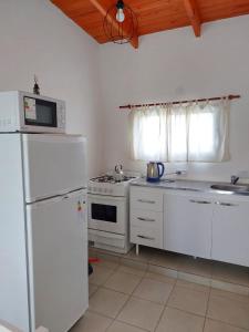 a white kitchen with a refrigerator and a microwave at La casita del campo in Colón