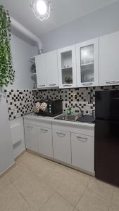 uma cozinha com armários brancos e um frigorífico preto em M&M's house em Tessalônica