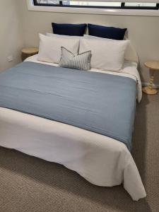 een groot bed met witte en blauwe lakens en kussens bij Coastal Pod in Port Macquarie