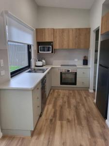 een keuken met witte werkbladen, houten vloeren en een wastafel bij Coastal Pod in Port Macquarie