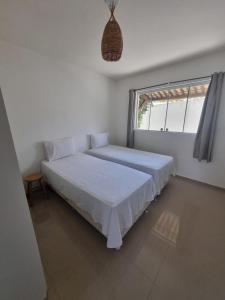 a white bedroom with two beds and a window at Condomínio Harmonia in Pipa +31 photos