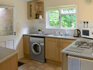 a kitchen with a sink and a washing machine at Satchwell Chalet on Reelig Estate near Inverness in Kirkhill