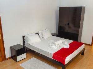 - une chambre avec un lit et une couverture rouge dans l'établissement Baig's Guest House, à São Tomé