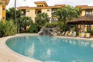 a swimming pool in front of a house at The Oaks Tamarindo Pool Front Condominiums fast wifi in Tamarindo