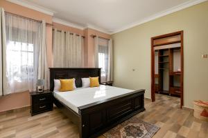 ein großes Schlafzimmer mit einem großen Bett mit gelben Kissen in der Unterkunft Delightful house Kampala Entebbe in Buzzi