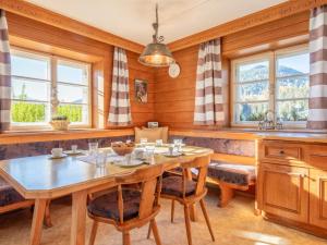 uma sala de jantar com mesa, cadeiras e janelas em Landhaus Platzl em Hopfgarten im Brixental