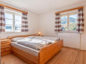 um quarto com uma cama de madeira e 2 janelas em Landhaus Platzl em Hopfgarten im Brixental