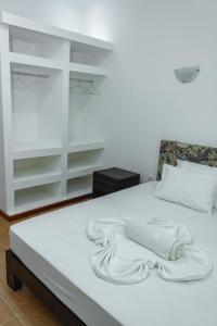 a white bed with a towel on top of it at Baig's Guest House in São Tomé