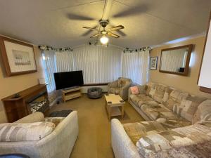 a living room with couches and a flat screen tv at 7 Rannoch Row, lovely holiday static caravan for dogs & their owners. in Forfar