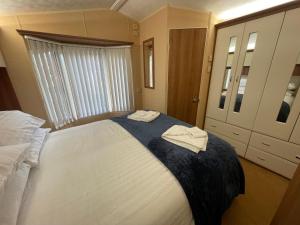 um quarto com uma cama grande com duas toalhas em 7 Rannoch Row, lovely holiday static caravan for dogs & their owners. em Forfar