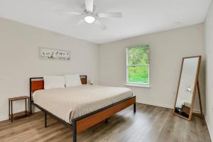 a white bedroom with a bed and a mirror at Modern home with garage near town in St. Augustine