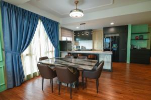 a dining room with a table and chairs and a kitchen at Santubong Suites Lower Level in Kuching