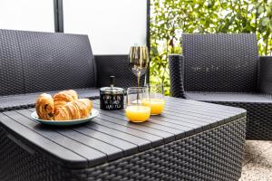 una mesa con un plato de bollería y vasos de zumo de naranja en Hortensia - Village calme Moderne à 10min de Disneyland, en Ferrières-en-Brie
