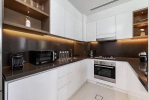 Luxurious 2BR apt with panoramic Marina view في دبي: مطبخ أبيض مع خزائن بيضاء وأجهزة