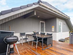 a patio with a grill and a table on a deck at Four-Bedroom Holiday home in Hemmet 14 in Falen