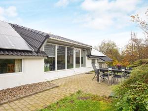 a house with a conservatory with a table and chairs at Four-Bedroom Holiday home in Hemmet 14 in Falen