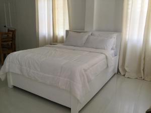 a white bed with white sheets and pillows at Gengs Apartment and Nmax Rentals in Dipolog