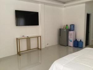 a room with a refrigerator and a tv on the wall at Gengs Apartment and Nmax Rentals in Dipolog