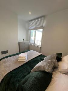 1 dormitorio con 1 cama con toallas en Seaforth Apartments 2 Bedroom Apartment with Parking and Garden by RockmanStays en Southend-on-Sea