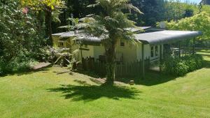 a small yellow house with a palm tree in the yard at Poihipi Farm Stay 