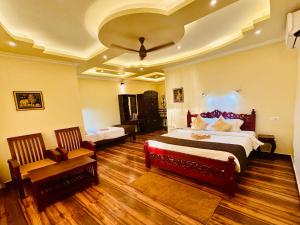 Maadathil Cottages & Beach Resort في فاركَالا: غرفه كبيره فيها سريرين وكرسي