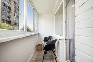 Habitación pequeña con silla y ventana en Tyzenhauzu Apartment en Vilna