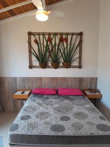 a bedroom with a bed with plants on the wall at Recanto da Praia Kitnetes in Caraguatatuba