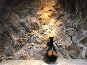 Czarna waza siedząca na stole przed kamienną ścianą w obiekcie A-HOME w mieście Jiufen