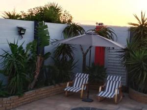 zwei Stühle und ein Regenschirm auf einer Terrasse in der Unterkunft R & E Good vibes in Kapstadt