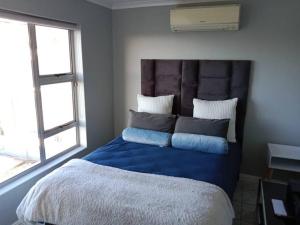 Schlafzimmer mit einem Bett mit blauer Bettwäsche und Kissen in der Unterkunft R & E Good vibes in Kapstadt + 9 Fotos