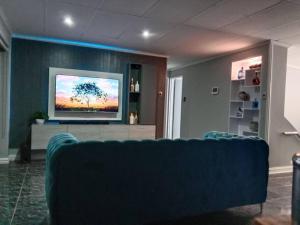 ein Wohnzimmer mit einer blauen Couch und einem Fernseher in der Unterkunft R & E Good vibes in Kapstadt