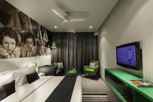 a bedroom with a bed and a flat screen tv at SinQ Party Hotel - No Male Stags Allowed in Candolim