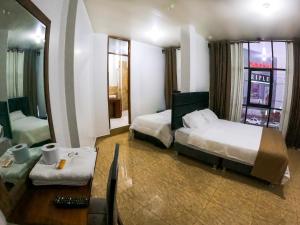 Habitación de hotel con 2 camas y espejo en HOTEL REAL PLAZA, en Cajamarca