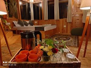 uma mesa com uma cafeteira e flores sobre ela em Tree House Jibhi The Hidden Cottage em Jibhi
