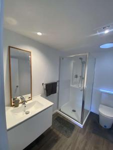 a white bathroom with a shower and a sink at Awa Tui Batch in Blenheim