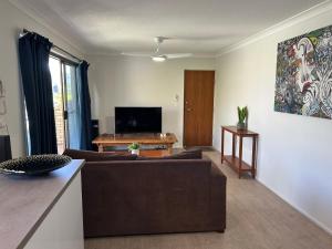 uma sala de estar com um sofá e uma televisão em Kirra Beach Unit em Gold Coast