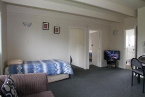 Schlafzimmer mit einem Bett und einem Flachbild-TV in der Unterkunft 252 Beachside Motels & Holiday Park in Hokitika