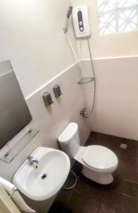 La salle de bains est pourvue de toilettes blanches et d'un lavabo. dans l'établissement Ginto Residence - City Center, à Coron