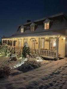 een huis met kerstverlichting in de sneeuw bij Auberge musicale Pour un Instant in La Malbaie