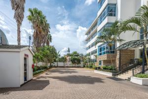 a street in front of a building with palm trees at Roma Court Serviced Apartments in Nairobi