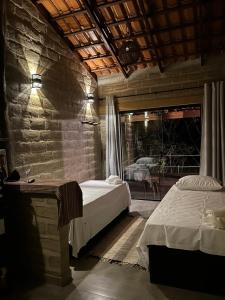 1 dormitorio con 2 camas y pared de piedra en Chalé Pousada Maná do Céu - São Jorge, en São Jorge