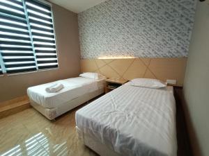 a bedroom with two beds and a window at Dane & Shue Hotel Kok Lanas in Kota Bharu