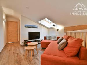 ein Wohnzimmer mit einem roten Sofa und einem TV in der Unterkunft Maison Saint-Jean-de-Sixt, 5 pièces, 10 personnes - FR-1-391-179 in Saint-Jean-de-Sixt