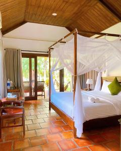 ein Schlafzimmer mit einem Himmelbett in einem Zimmer in der Unterkunft Thanh Kieu Beach Resort in Phu Quoc