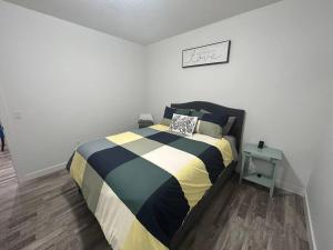 a bedroom with a bed with a striped comforter at Seton Villas Cozy (Lower) Suite in Calgary