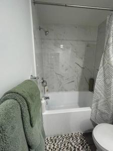 a bathroom with a tub and a toilet and a shower at Seton Villas Cozy (Lower) Suite in Calgary