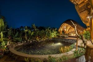 a pool in the middle of a garden at night at Arapan Ubud Eco Villa in Ubud