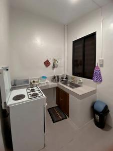 a white kitchen with a stove and a sink at The Doll House 2.0 in Abucay